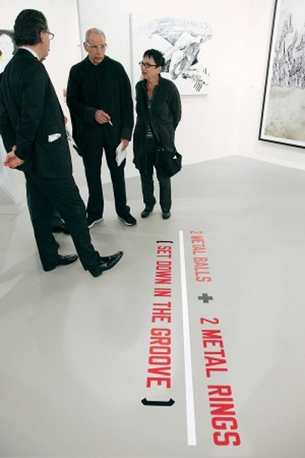 Аарон и Барбара Левайны на Art Basel рядом с работой Лоуренса Вайнера  Источник: newsweek.com